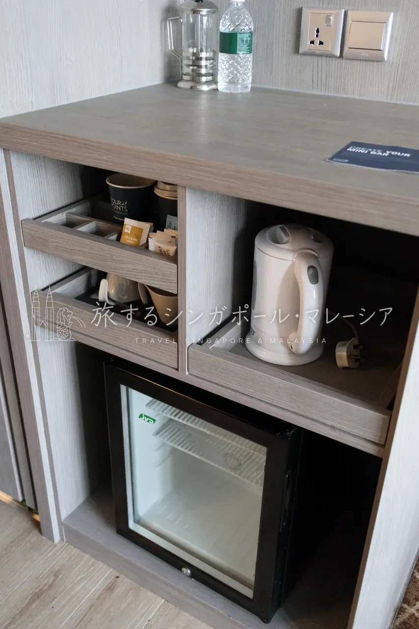 左:窓際にはソファ(デイベッド)付きのワークデスク。窓の外には「M SOCIAL」のビルや川沿いの街並み。右:「FOUR POINTS」ロゴ入りのコーヒー・ティーセットとミニバー。
