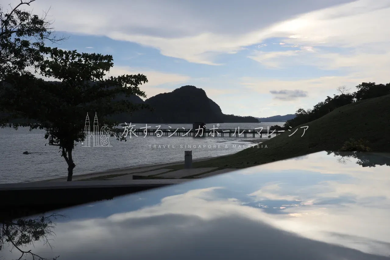 夕暮れのインフィニティプール。水面に雲と島影が映り込み、桟橋の延びる入り江まで一続きに見えます。これがいちばんの絶景。