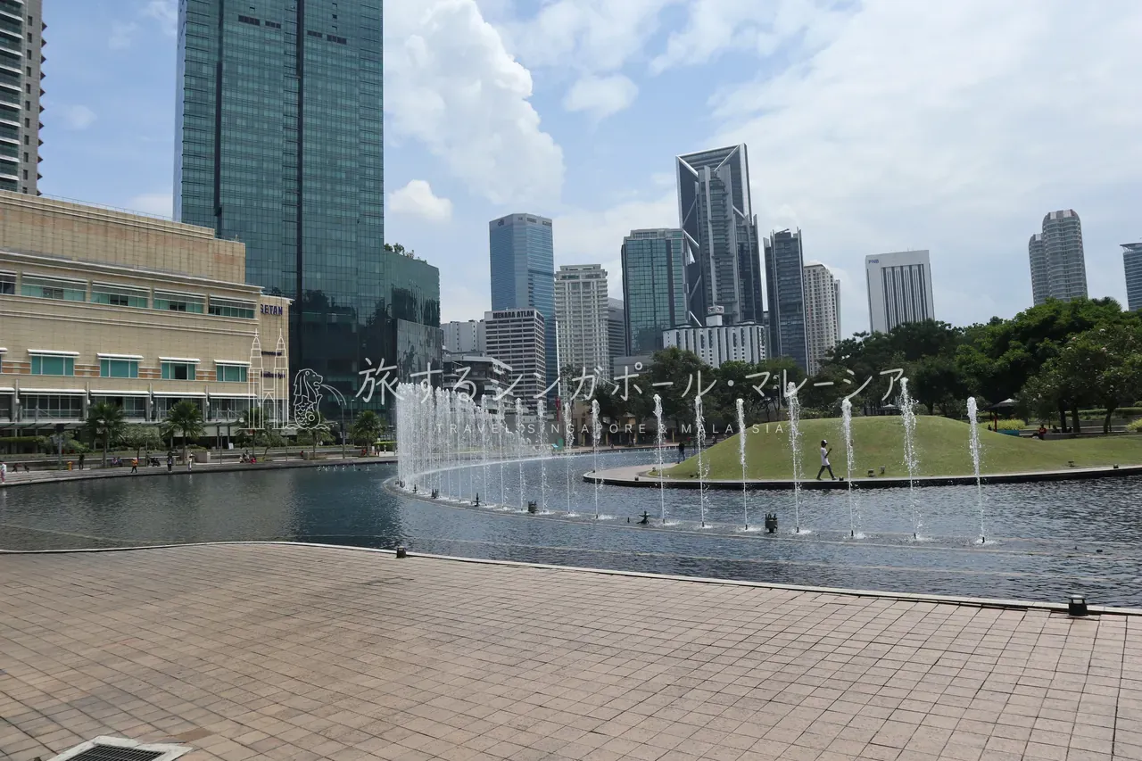 左：水遊び場のつづき。暑いマレーシアの公園らしい光景です。右：公園の中心にある人工池。昼間は静かで、奥の高層ビル群との対比が綺麗。夜はここで噴水ショーが行われます。