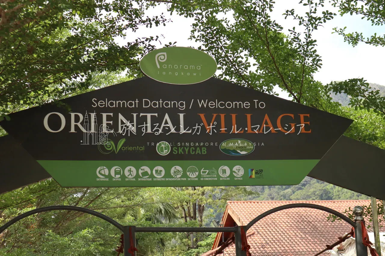 麓のゲートに掲げられた「Welcome To ORIENTAL VILLAGE」の看板。ここがケーブルカー（Langkawi SkyCab）の玄関口。背後にはもうマッチンチャンの山肌が迫ります。