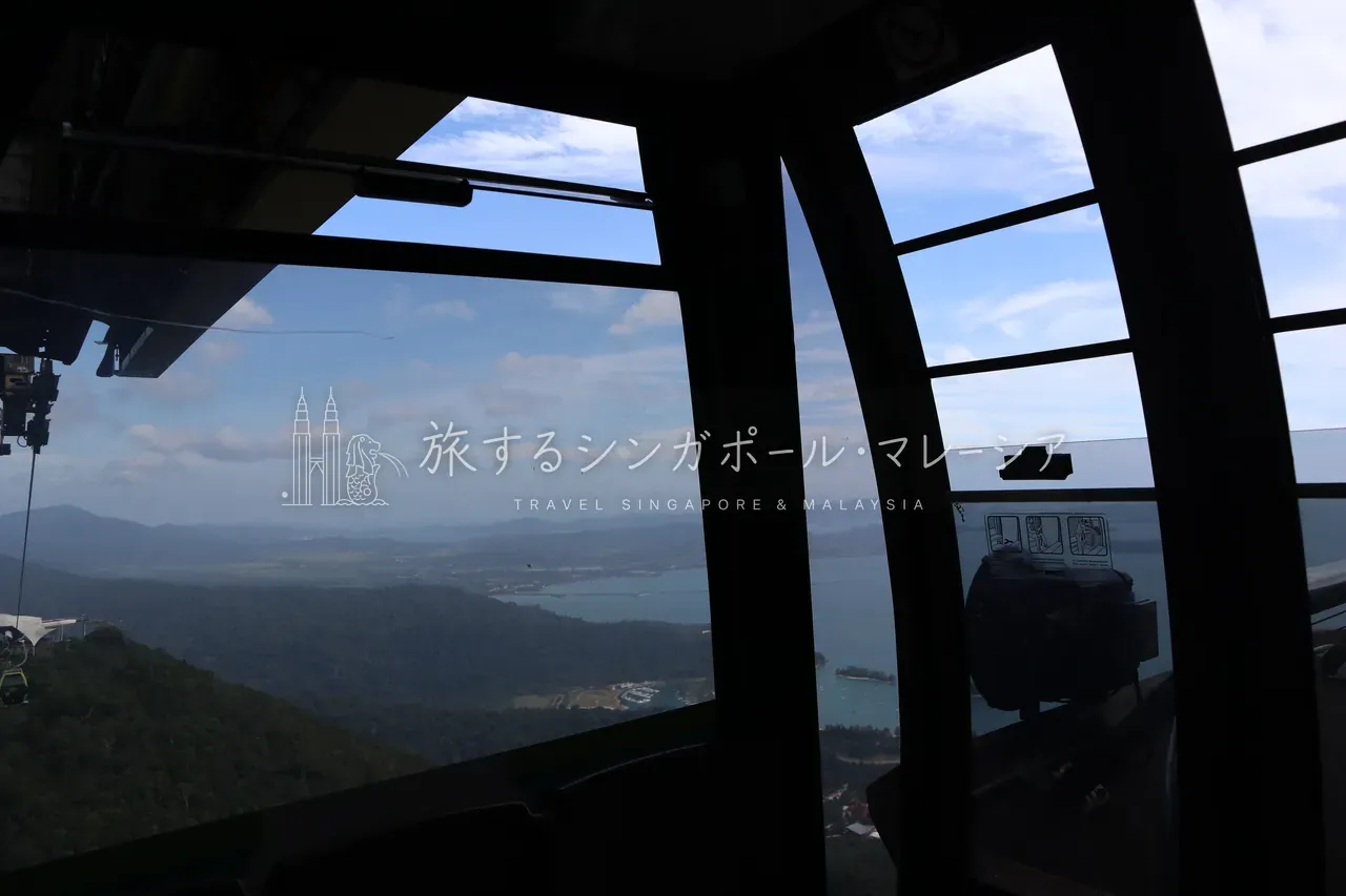 左:険しいジャングルの山肌を昇っていくゴンドラ。マッチンチャンの断崖の迫力に圧倒されます。右:ゴンドラ内から窓越しに望むランカウイ島。昇る過程からもう絶景です。
