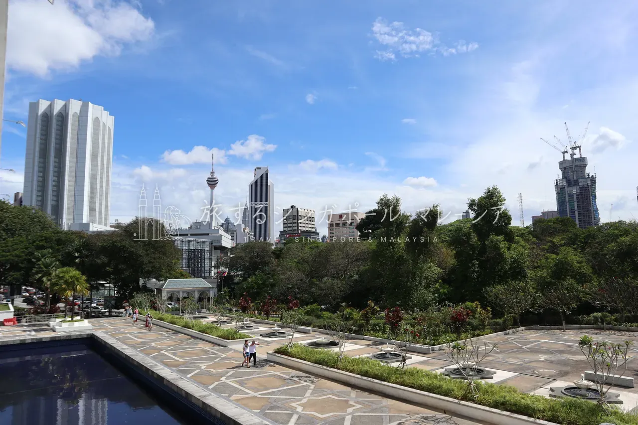 幾何学式の庭園と反射池の向こうに、KLタワーや高層ビル。緑・水・モダン建築・摩天楼がひとつの画面に収まる、マスジッド・ネガラならではの眺めです。