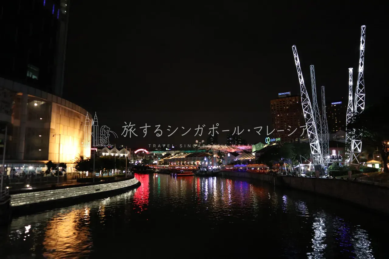 左：川の上流側を望むと、川岸に何本もの逆バンジーの塔。背後はノボテル＆サマセット。右：緑のエンジェル屋根とバンボート。川を行き来する観光ボートが、夜の川辺に彩りを添えます。