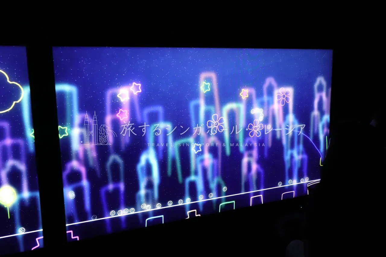 左:ネオン色の街並みを描いた映像の暗室。右:虹色の光に満ちた水族館映像の空間で、来場者も思わずカメラを向けます。