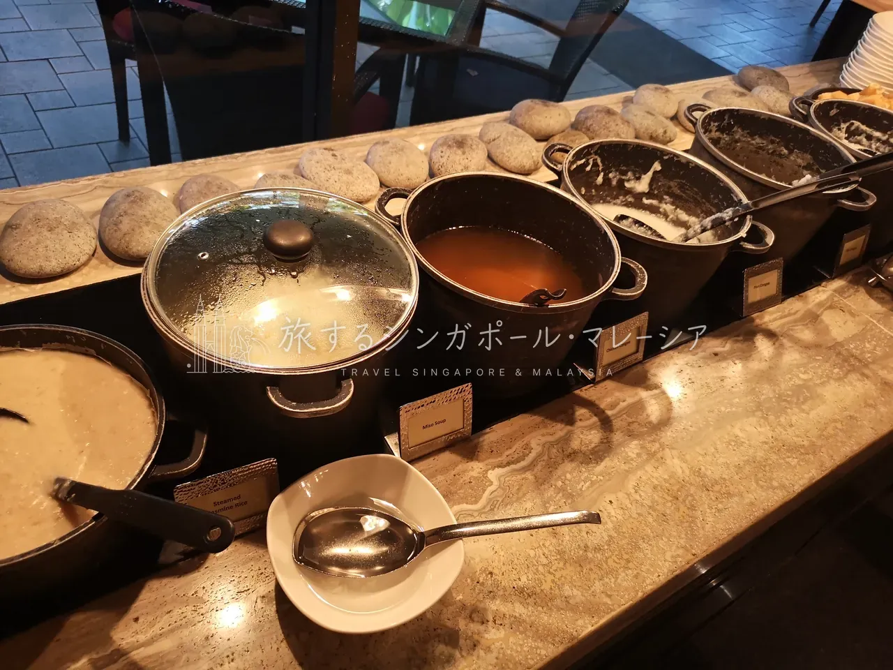 左：ホットミールは種類豊富。お肉系もがっつり。右：おかゆも数種類、まさかのミソスープまで揃う不思議な並び。