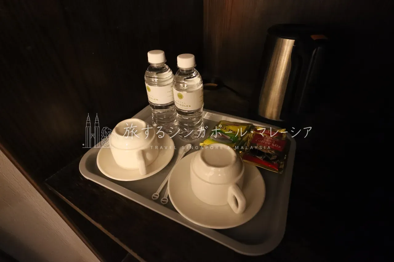 左:鏡付きのドレッサー・デスクと籐のチェア。右:「HOTEL BENCOOLEN」ロゴ入りのミネラルウォーターやミルクティー・コーヒー、電気ケトルがそろうティートレイ。