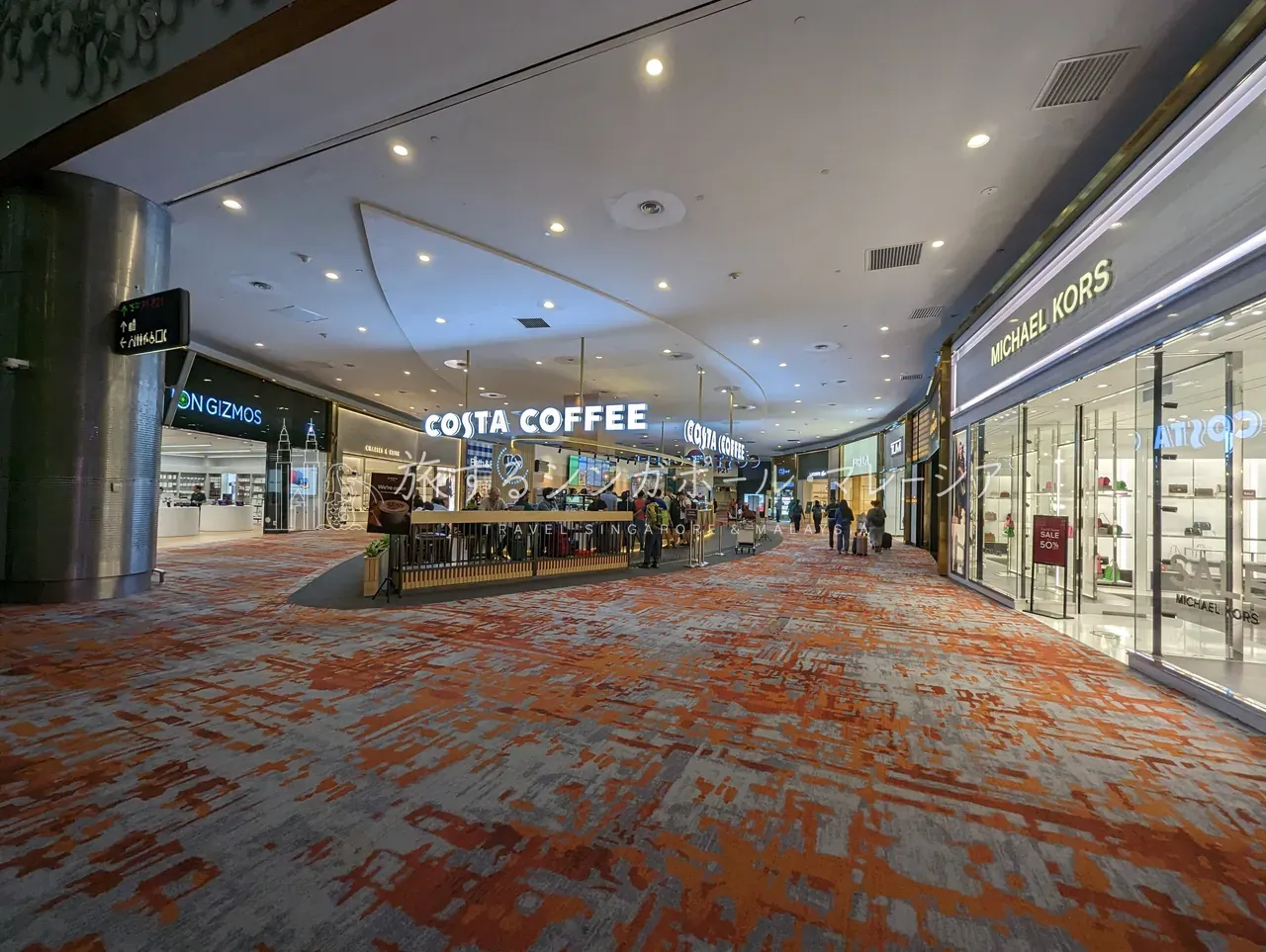 Terminal 1の制限エリア側に続く、複数階吹き抜けの免税・ショッピングゾーン。Costa CoffeeやMichael Korsなど各種店舗が並びます。本館は『歩く距離が長い』のも特徴なので、乗り継ぎは時間に余裕を持って。